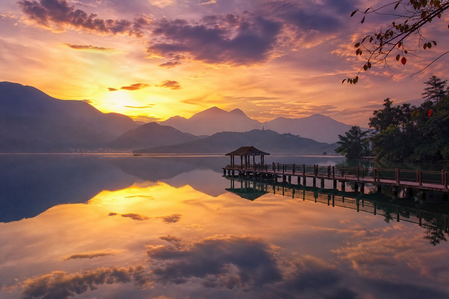 日月潭秋天夕陽，湖面如鏡倒映金色霞光與層層山巒