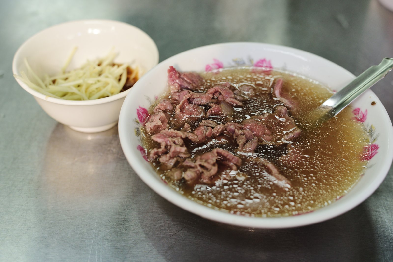 現切溫體牛肉淋上滾燙高湯的台南牛肉湯，清晨攤位木桌晨光